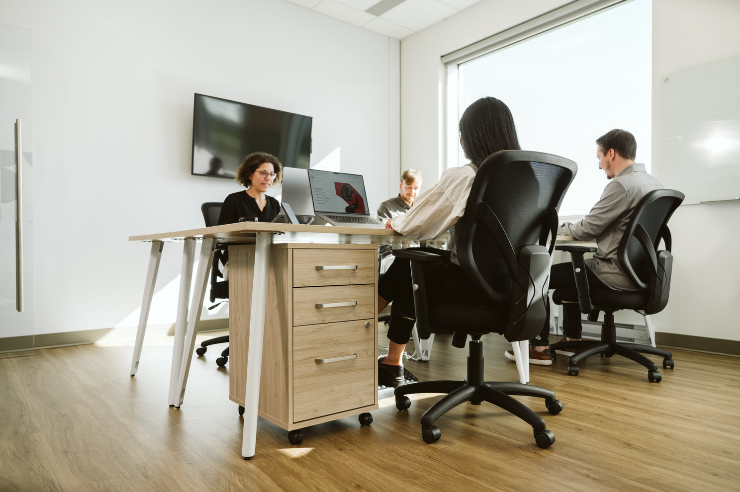A group of employees in the office working at open table desks from the Vista collection by BBF.