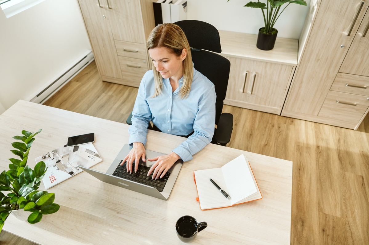 Woman working on a laptop at a desk in a modern office setting