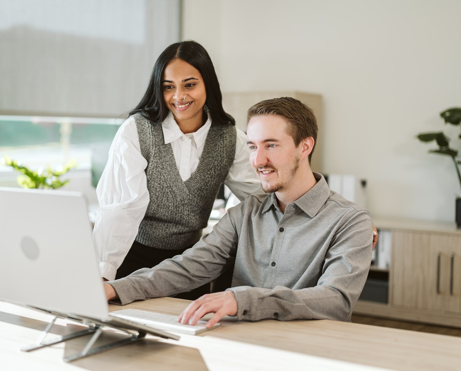 Two people working together on a computer in an office setting